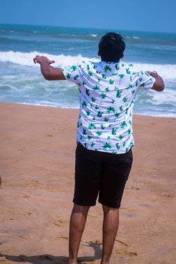 Sırtı sahilde duran genç bir adam..