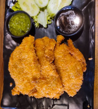 Bir tabak kızarmış balık ve yanında sebze.