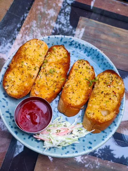 Porselen bir tahtada peynir soslu sarımsaklı ekmek