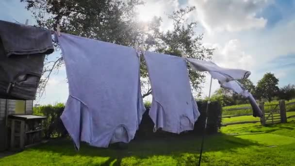 晴れた日のアウトドアハウスワークのシーンは 青い空の背景にラインにぶら下がる新鮮な洗濯された服 このイメージは清潔さと新鮮さの本質を捉えています — ストック動画