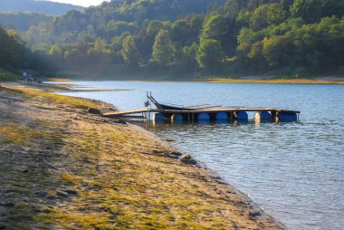 Solina Gölü 'ndeki varillerdeki ahşap köprünün manzarası. Her yerde bir orman var. Kıyıdaki insanlar. Polonya, Bieszczady Dağları 'nda yaz mevsimi.