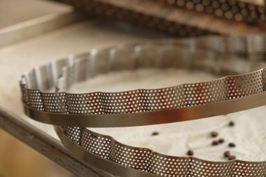 Zanaatkarlar, hareketli bir öğleden sonra boyunca sanatsal ekmek yapma becerileriyle tanınan sıcak, güneşli bir mutfakta karmaşık metal pişirme kalıpları yaratırlar.