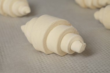 Taze yapılmış kruvasan hamuru sıcak bir mutfakta pişirilmeyi bekliyor. Kahvaltıdan hemen önce hassas katmanlar ve zanaatkarlık sergiliyorlar.