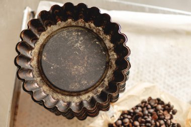 Rusty pastry molds arranged on a surface with scattered coffee beans nearby, evoking a sense of nostalgia and culinary creativity in a rustic kitchen clipart