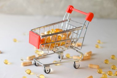 Yüzeyde renkli vitamin kapsülleriyle dolu minyatür alışveriş arabası