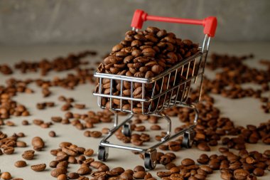 Kahve çekirdekleri sanatsal bir arka planda küçük bir alışveriş arabasını doldurur.