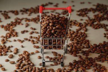 Hafif bir yüzey boyunca minyatür bir alışveriş arabasından kahve çekirdekleri taşar.