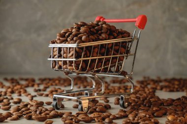 Kahve çekirdekleri, ahşap bir yüzeyde bir alışveriş arabasını dağınık fasulyelerle doldurur.