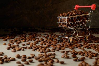 Kahve çekirdekleri kırsal bir ortamda minyatür bir alışveriş arabasının etrafına saçılmış.