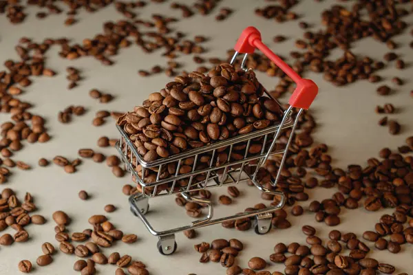 Yumuşak bir arka planda kavrulmuş kahve çekirdekleri ile dolu alışveriş arabası.