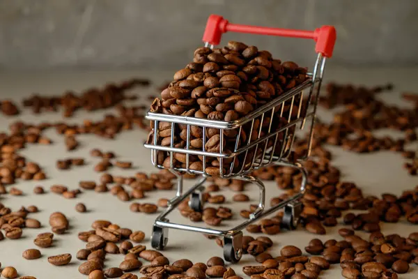 Kahve çekirdekleri sanatsal bir arka planda küçük bir alışveriş arabasını doldurur.
