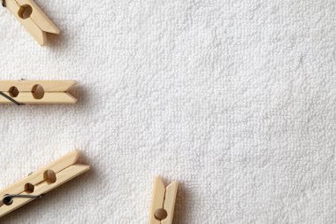 Ahşap mandallar, yumuşak beyaz kumaş arka planda sanatsal olarak dizilmiş.