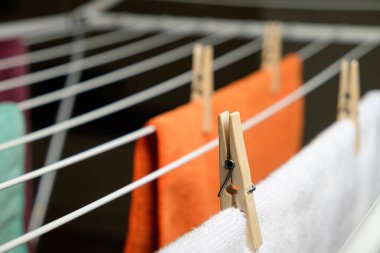 Çamaşır mandalları, güneşli bir öğleden sonra kurutma rafında canlı havlular emniyete alır.