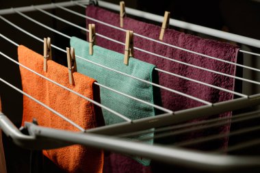 Parlak renkli havlular bir elbisenin üzerinde asılı ahşap mandallarla kurutma askısı.