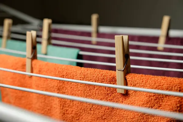 Renkli çamaşır mandalları sıcak bir iç mekanda asılı duran canlı havlular.