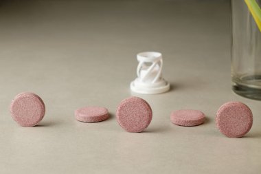 Canlı pembe tabletler, cam ve samanların yanında sıraya dizilmiş.