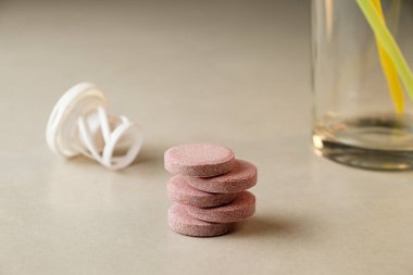 Tezgahın üzerine yığılmış renkli tabletler bir bardak suyun yanında.