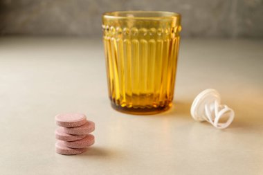 Minimalist bir tezgahta eski bir camın yanına istiflenmiş haplar.