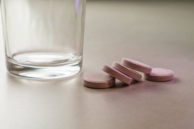 Sakin bir sabah saatinde masanın üstündeki bir bardağın yanında dinlenen haplar.