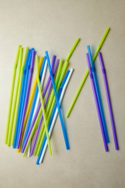 Parlak renkli plastik pipetler pürüzsüz bir ışık yüzeyinde gelişigüzel uzanır.