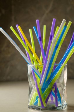 Renkli pipetler tarafsız bir arkaplanda bir bardakta canlı bir görüntü oluşturur