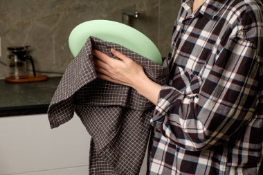 Sabah rutininde sıcak bir mutfak ortamında ellerin tabak ve havlu tutuyor.