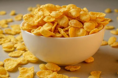 Mutfak tezgahındaki kaseden dökülen gevrek mısır gevrekleri.