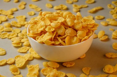 Keyifli mısır gevrekleri bir kâsenin etrafına saçılmış sıcacık bir kahvaltı sofrasında