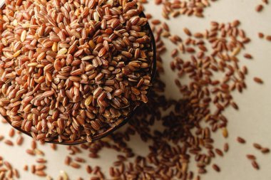 Ahşap bir yüzeyde, kırsal bir kaseden taşan organik kahverengi pirinç.