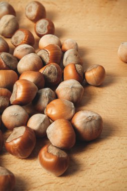 Taze fındıklar, yumuşak kabukları ve zengin kahverengi renklerini ortaya çıkararak, kırsal ahşap bir yüzeye yayılır. Bu fıstıkların doğal güzelliği sahneye sıcak bir dokunuş katıyor..