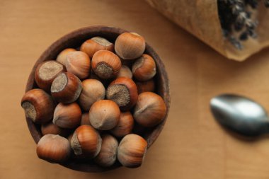 Taze toplanmış fındıklar pürüzsüz ahşap bir masada basit bir ahşap kaseyi doldurur. Yakınlarda bir miktar lavanta duruyor, doğal hayata biraz renk katıyor..