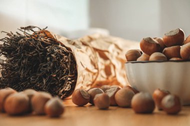 Sıcak bir mutfak sahnesinde bir kase fındık ve kurumuş bitkilerin yanında. Yumuşak güneş ışığı, sonbahar rahatlığı ve yemek pişirme ilhamını çağrıştırıyor..