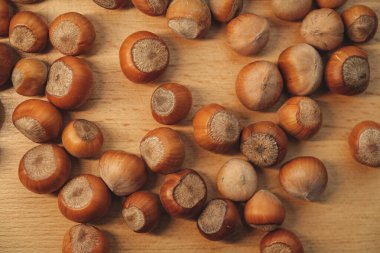 Pürüzsüz bir tahta masanın üzerine serpilmiş taze fındık koleksiyonu zengin kahverengi kabuklarını sergiliyor. Lezzetli yemek tarifleri için mükemmel. Sıcak ve ev yemeği hissi uyandırıyorlar..