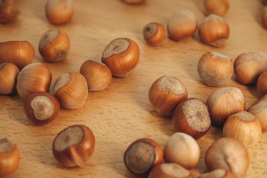 Kahverenginin çeşitli tonlarında fındıklar kırsal bir ahşap masaya rastgele yayılır. Doğal ışık, bu fındık hasadının güzelliğini gözler önüne sererek pürüzsüz dokularını ön plana çıkarıyor..