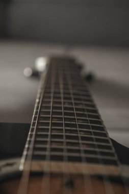 Focusing on the intricate details of a guitar, the view captures the strings and fretboard from a low angle. The warm tones of the wood showcase the craftsmanship, inviting musical creativity.