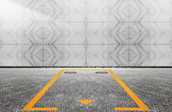 An empty parking space sits between a tiled wall and an asphalt floor
