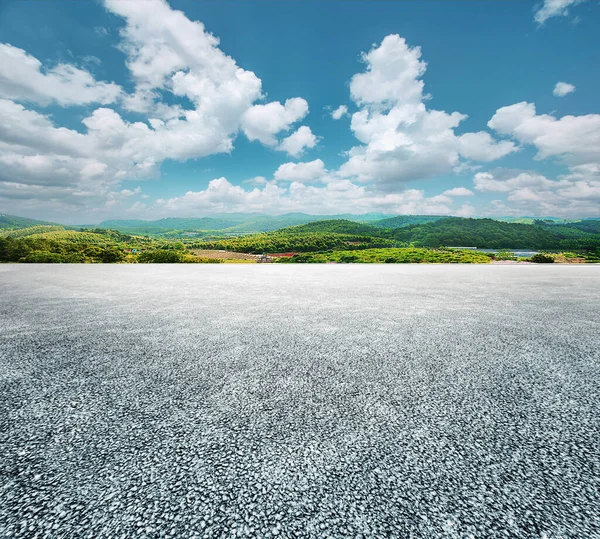 Asphalt road and green mountain nature landscape under blue sky with white clouds