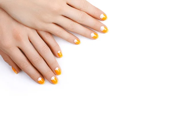 Beautiful Female Hands with bright Orange Manicure like Candy Corn on Yellow Background. Manicured Nails with Creative Gel Polish Design. Halloween Style