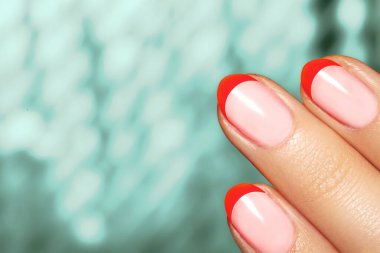 Noel sezonu için kırmızı akrilik tırnaklı bir kadın eli. Fransız manikürü. Mutlu noeller. Noel partileri için güzel tırnaklar