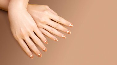 Beautiful Female Hands with bright Orange Manicure like Candy Corn on Yellow Background. Manicured Nails with Creative Gel Polish Design. Halloween Style