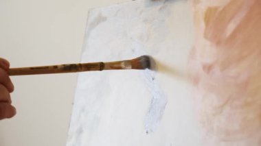 Sanatçı el nazikçe tuvale boya karıştırır. Yumuşak fırça hareketleri doku yaratır. Canlı bir palet huzurlu resim sahnesini tamamlıyor..