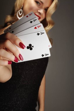 Kadınların elinde kağıt oynayan dört as. Poker dörtlü kombinasyonu olan bir oyuncu. Tırnaklarında kırmızı manikür olan zarif kadın elleri..