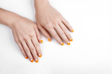 Mısır şekeri gibi parlak turuncu manikürlü kadın elleri. Beyaz arka planda yaratıcı jel tırnak tasarımı. Cadılar Bayramı tırnak sanatı, moda güzelliği ve şık manikür konsepti. Parlak Turuncu Manikürlü Güzel Kadın Elleri Şeker Mısır Gibi