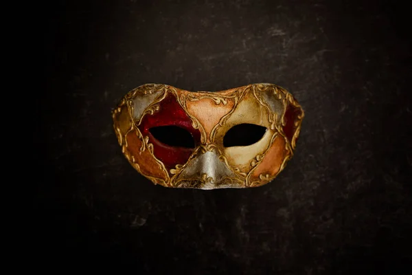 Vibrant Venice mask on dark background. High quality photo. Venetian mask decorated with quality paints. Carnival mask.