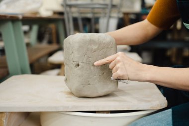 Potter, Seattle, Washington 'daki seramik stüdyosunda kil kesiyor. Yüksek kalite fotoğraf. Yan görüş. Kadın çömlekçi.