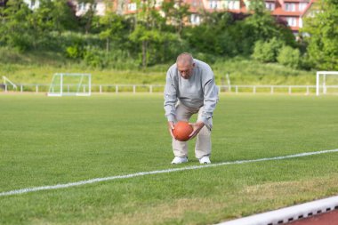 Yaşlı bir adam bir yaz akşamı stadyumun arka planında spor için içeri girer.