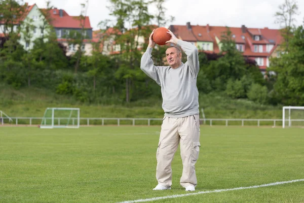 An elderly man goes in for sports on the background of the stadium on a summer evening