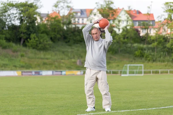 Yaşlı bir adam bir yaz akşamı stadyumun arka planında spor için içeri girer.