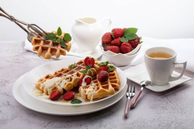 Viyana waffleları, beyaz bir tabakta açık güneşli bir arka planda çilekli.