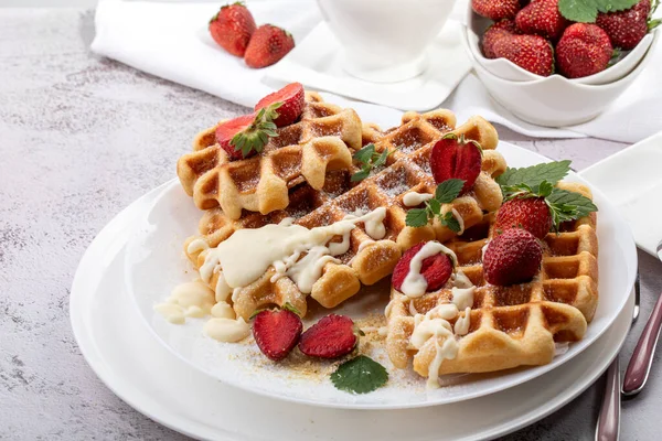 Viyana waffleları, beyaz bir tabakta açık güneşli bir arka planda çilekli.